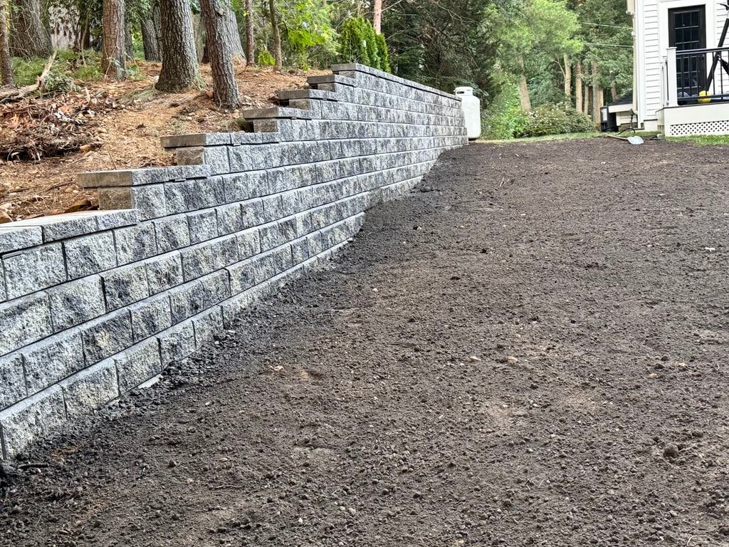 Completed segmental block retaining wall with freshly graded yard in Beverly, MA
