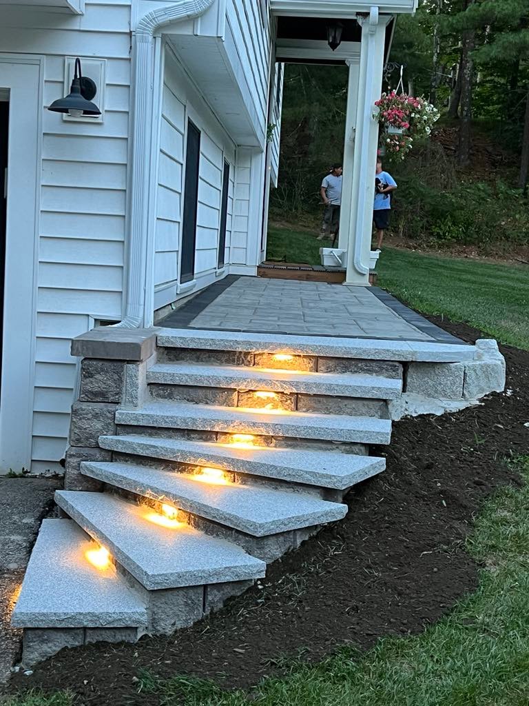 Illuminated granite entry steps with stone veneer walls and paver landing completed in Marblehead, MA